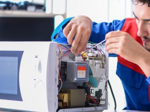 A technician repairing internal components of a microwave, addressing problems such as the microwave not heating.