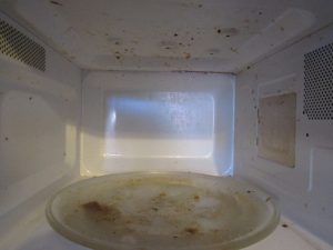 A microwave in need of a clean, with burnt food causing an unpleasant smell.