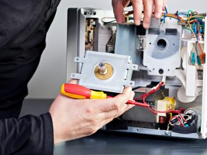 A man repairing a microwave that smells burnt, addressing issues to eliminate unpleasant odours and restore functionality.