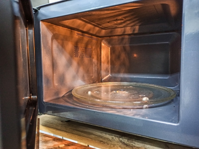 Dirty microwave interior with food residue, often a sign of a faulty microwave affecting safety and performance.
